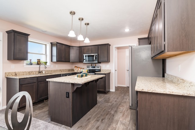 kitchen featuring appliances with stainless steel finishes, dark brown cabinets, a center island, dark hardwood / wood-style flooring, and decorative light fixtures