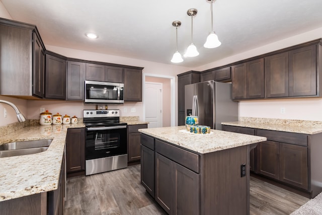 kitchen with dark wood-type flooring, hanging light fixtures, sink, a center island, and appliances with stainless steel finishes