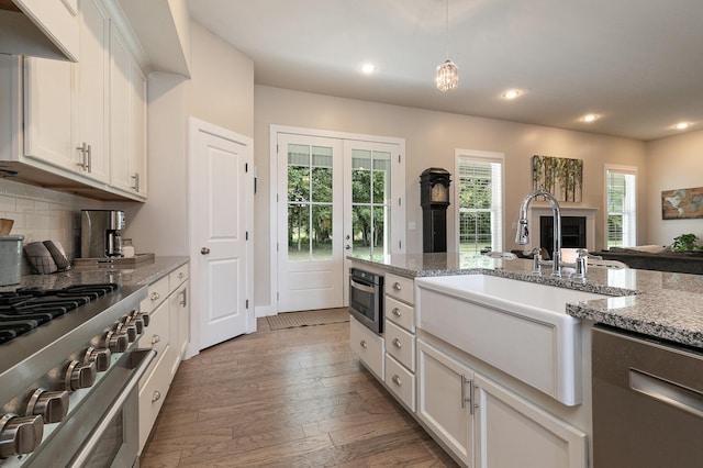 kitchen featuring stainless steel appliances, light stone countertops, dark hardwood / wood-style flooring, and white cabinetry