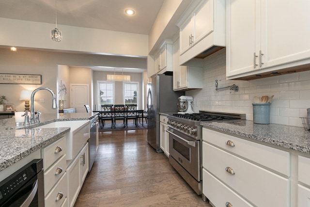 kitchen featuring dark wood-type flooring, hanging light fixtures, white cabinets, and appliances with stainless steel finishes