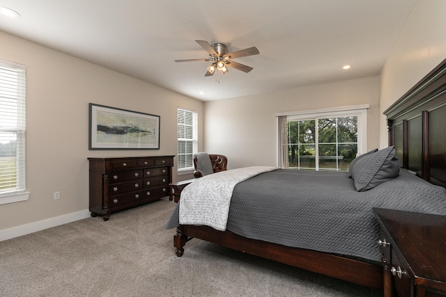 bedroom with multiple windows, ceiling fan, and light colored carpet