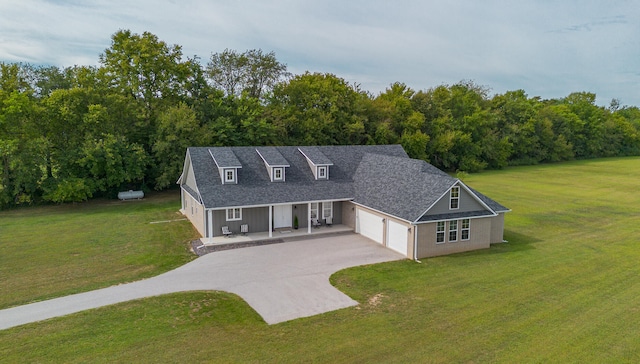 view of front of property featuring a front lawn, covered porch, and a garage