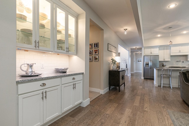 kitchen featuring white cabinets, stainless steel fridge with ice dispenser, dark hardwood / wood-style flooring, and light stone counters