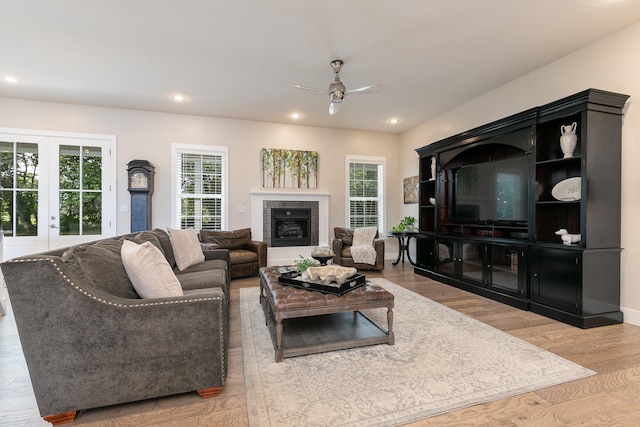 living room with ceiling fan, a fireplace, plenty of natural light, and light hardwood / wood-style flooring