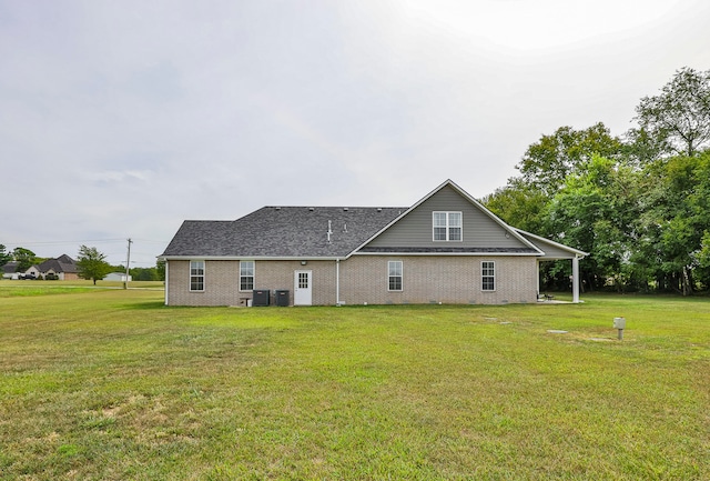 rear view of property featuring central air condition unit and a yard