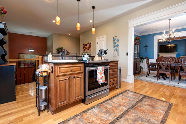 kitchen with light hardwood / wood-style floors, electric range, sink, hanging light fixtures, and a center island