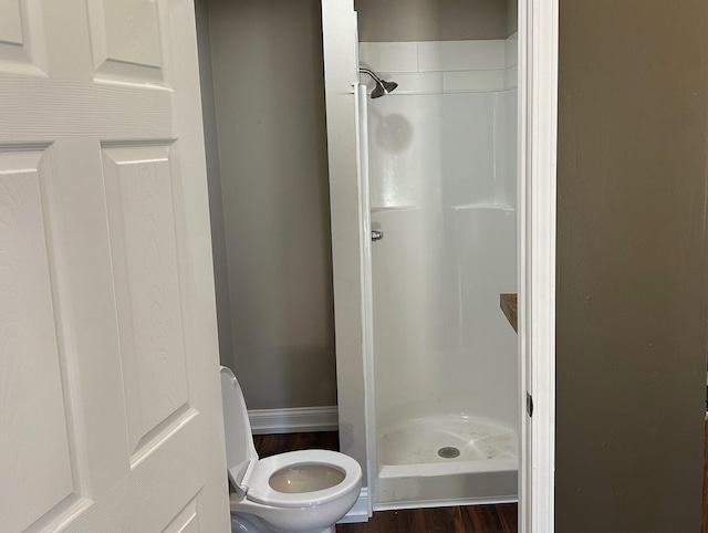 bathroom featuring walk in shower, hardwood / wood-style floors, and toilet