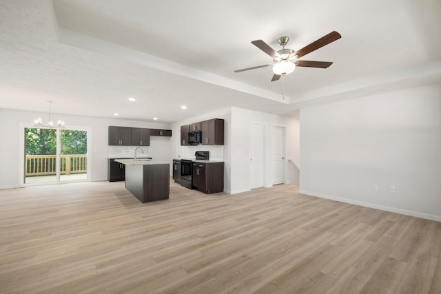 kitchen with light hardwood / wood-style floors, a kitchen island with sink, ceiling fan with notable chandelier, hanging light fixtures, and black appliances