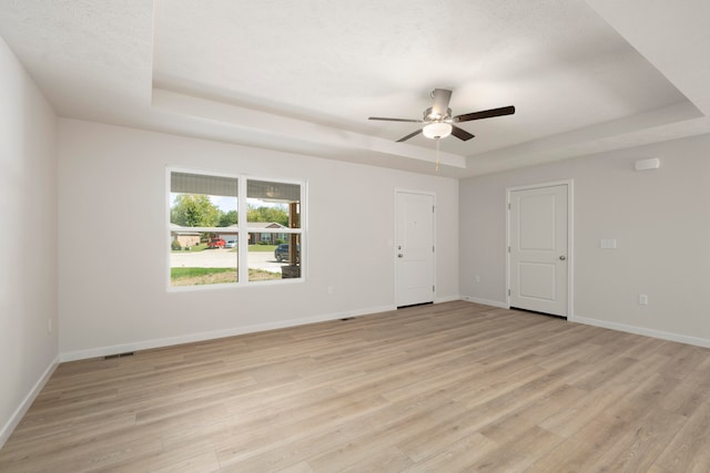 spare room featuring ceiling fan, light hardwood / wood-style flooring, and a raised ceiling