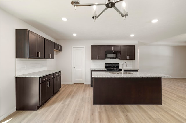 kitchen with light hardwood / wood-style floors, dark brown cabinetry, sink, light stone countertops, and black appliances