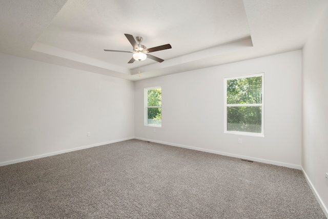 spare room featuring ceiling fan, carpet floors, and a raised ceiling