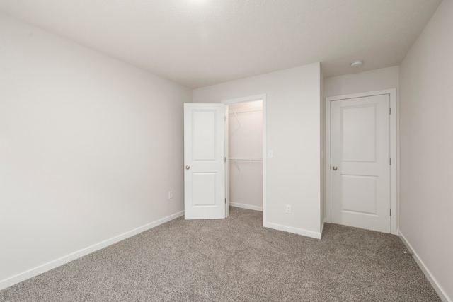 unfurnished bedroom with carpet floors, a spacious closet, and a closet