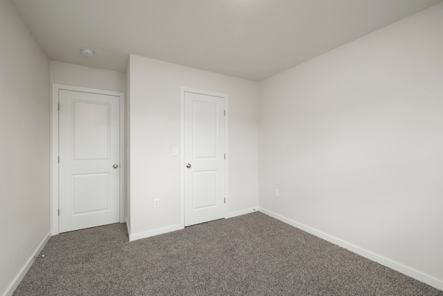 unfurnished bedroom featuring dark colored carpet and a closet