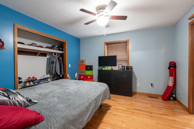 bedroom featuring a closet, light hardwood / wood-style flooring, a textured ceiling, and ceiling fan