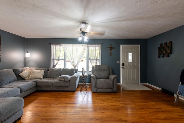 living room featuring ceiling fan, hardwood / wood-style flooring, and a textured ceiling