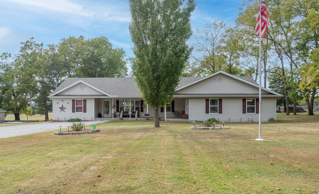 ranch-style house featuring covered porch and a front yard