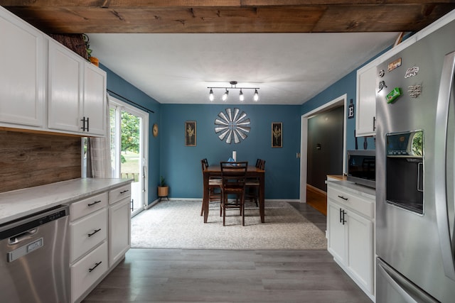 kitchen featuring appliances with stainless steel finishes, hardwood / wood-style flooring, beamed ceiling, and white cabinets