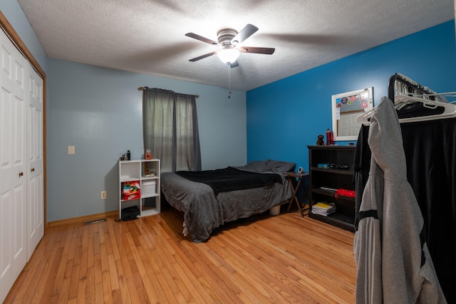 bedroom with a textured ceiling, ceiling fan, a closet, and light hardwood / wood-style flooring