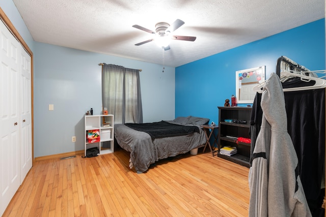 bedroom with ceiling fan, a closet, wood-type flooring, and a textured ceiling