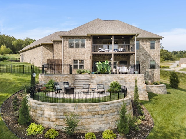 rear view of property featuring a balcony, a yard, and a patio