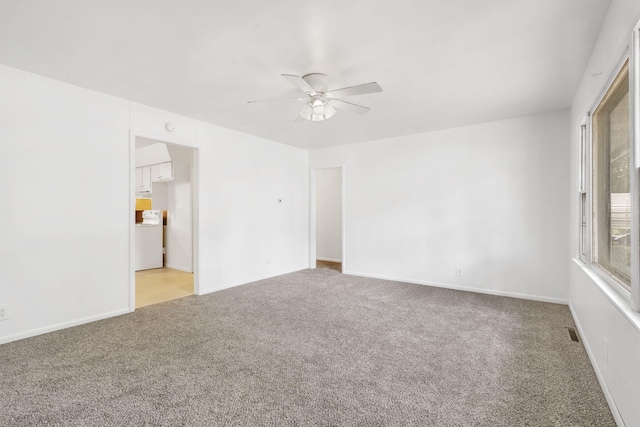 empty room with washer / clothes dryer, light colored carpet, and ceiling fan