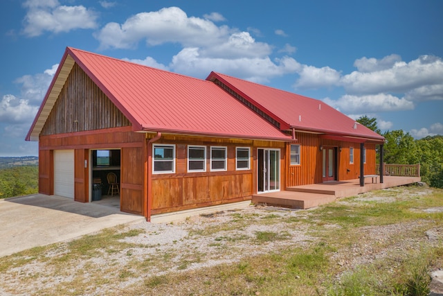 rear view of property featuring a garage and a wooden deck