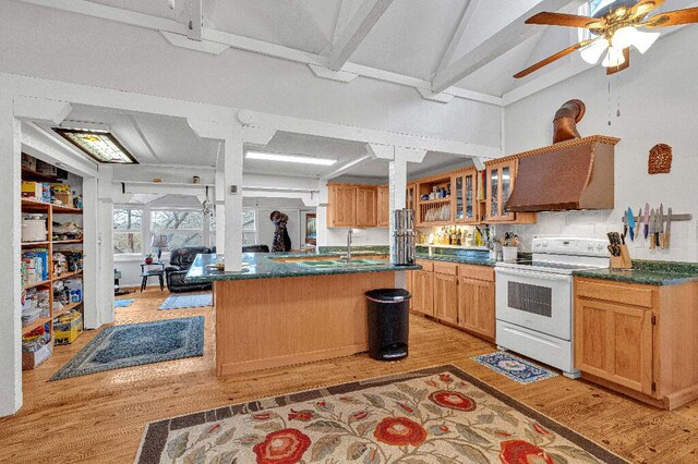 kitchen with range, light hardwood / wood-style floors, a kitchen island with sink, and custom exhaust hood