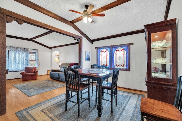 dining space featuring a textured ceiling, hardwood / wood-style flooring, vaulted ceiling, and ceiling fan