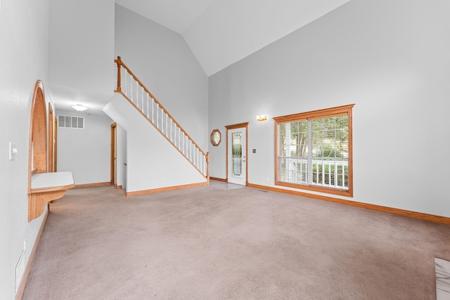 unfurnished living room featuring light colored carpet and high vaulted ceiling