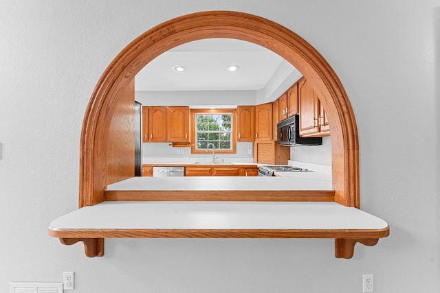 kitchen with arched walkways, dishwasher, brown cabinets, and a sink