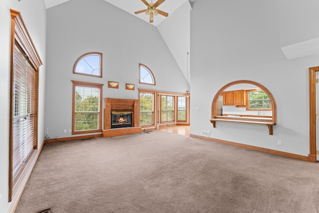 unfurnished living room with light carpet, visible vents, high vaulted ceiling, and a sink