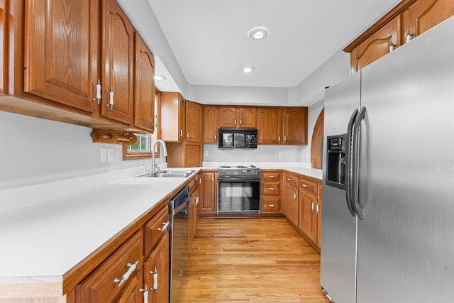 kitchen with light countertops, a sink, brown cabinets, and black appliances