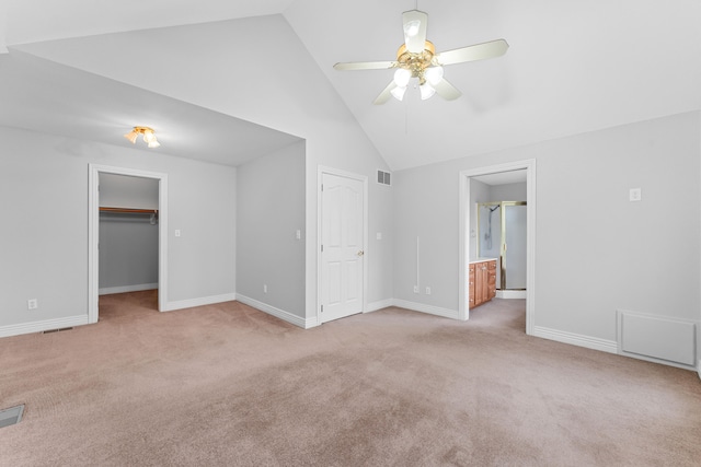 unfurnished bedroom with ensuite bath, ceiling fan, a spacious closet, and light colored carpet