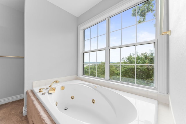 bathroom with a relaxing tiled tub and plenty of natural light