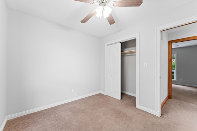 unfurnished bedroom with a ceiling fan, baseboards, a closet, and light colored carpet