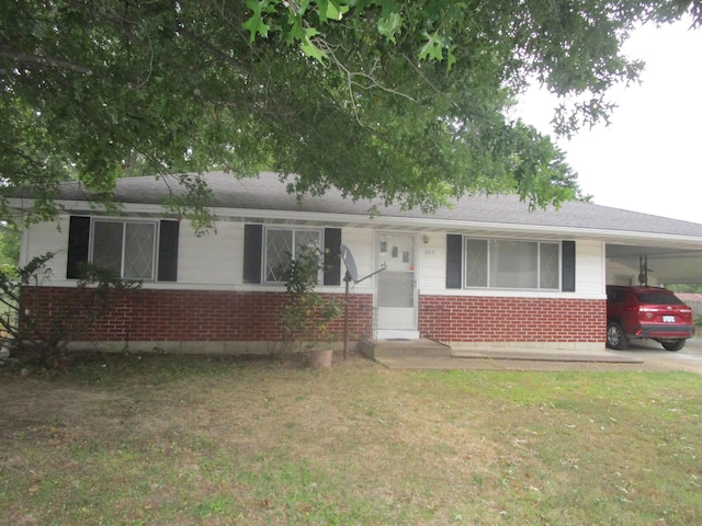 ranch-style home featuring a front lawn, brick siding, and an attached carport