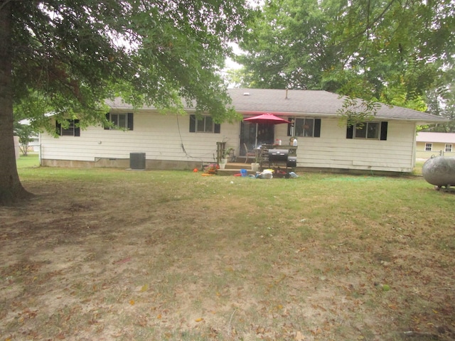 rear view of house with central AC and a lawn