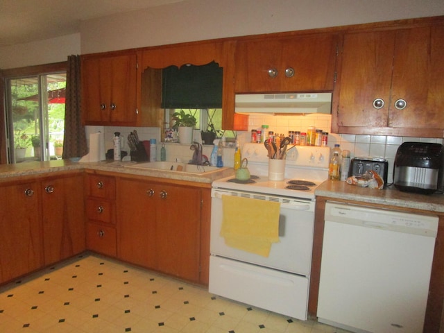 kitchen with decorative backsplash, white appliances, and sink