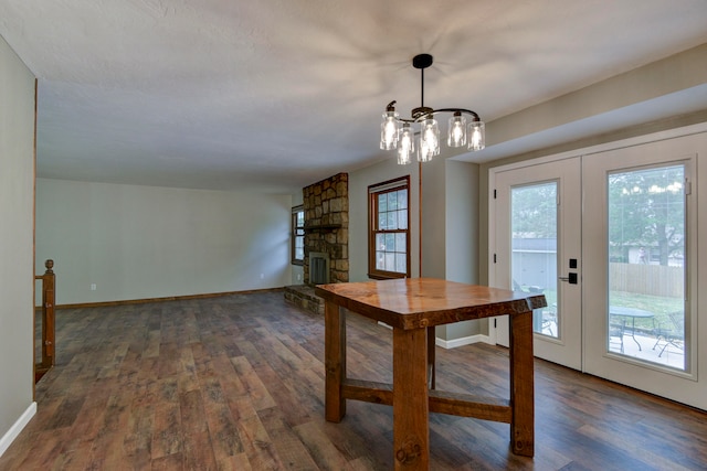 unfurnished dining area featuring a fireplace, french doors, an inviting chandelier, and dark hardwood / wood-style flooring