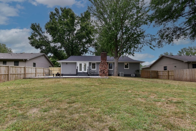 rear view of house with central air condition unit and a lawn