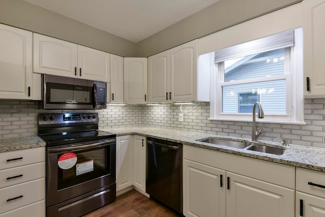 kitchen with light stone counters, white cabinets, stainless steel appliances, and sink