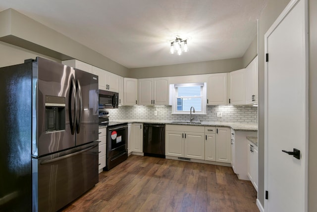 kitchen with black appliances, dark hardwood / wood-style floors, tasteful backsplash, white cabinets, and sink