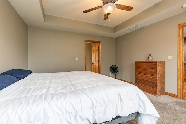 bedroom featuring ceiling fan, a raised ceiling, and light carpet