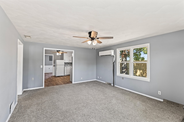 unfurnished bedroom featuring a wall unit AC, dark colored carpet, white fridge, and ceiling fan