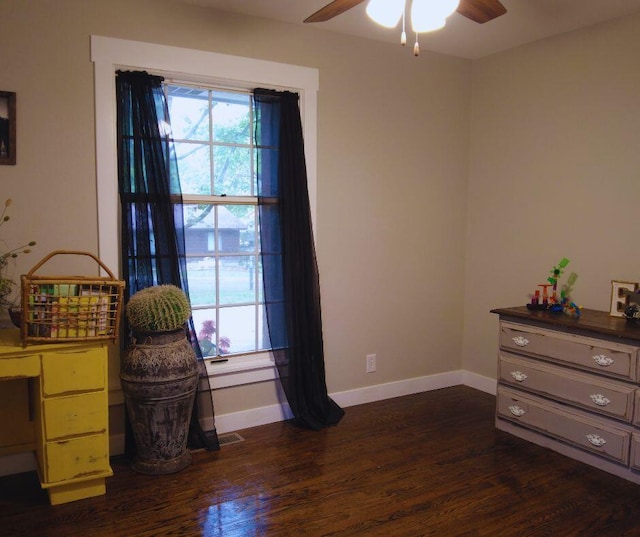 interior space with baseboards, a ceiling fan, and dark wood-style flooring
