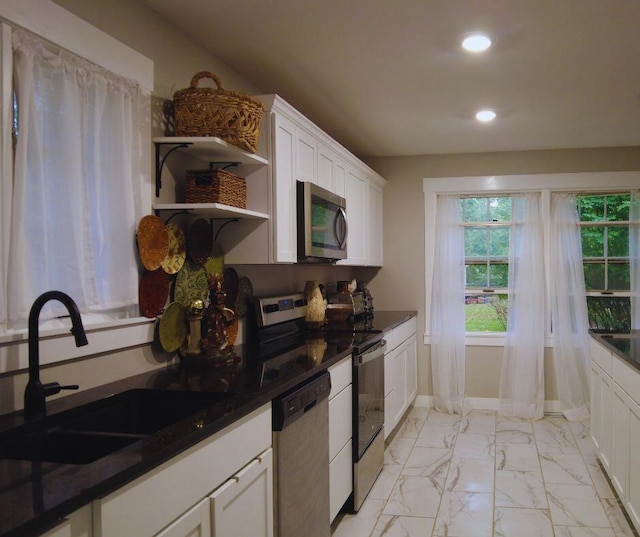 kitchen featuring dark countertops, a sink, stainless steel appliances, white cabinets, and recessed lighting