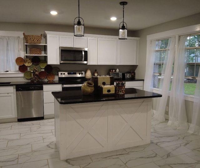 kitchen featuring hanging light fixtures, appliances with stainless steel finishes, a kitchen island, and white cabinetry