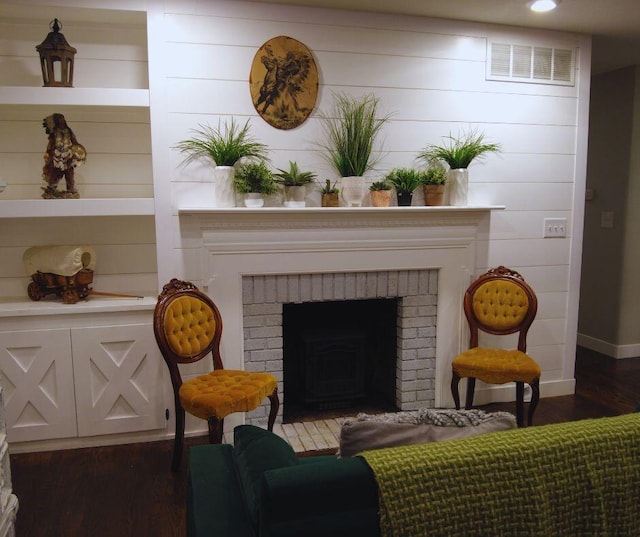 living area featuring dark wood finished floors, baseboards, a brick fireplace, and visible vents