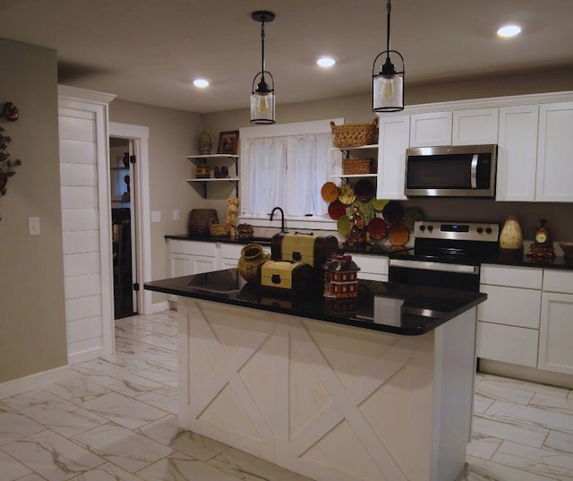 kitchen with appliances with stainless steel finishes, a kitchen island, decorative light fixtures, and white cabinets