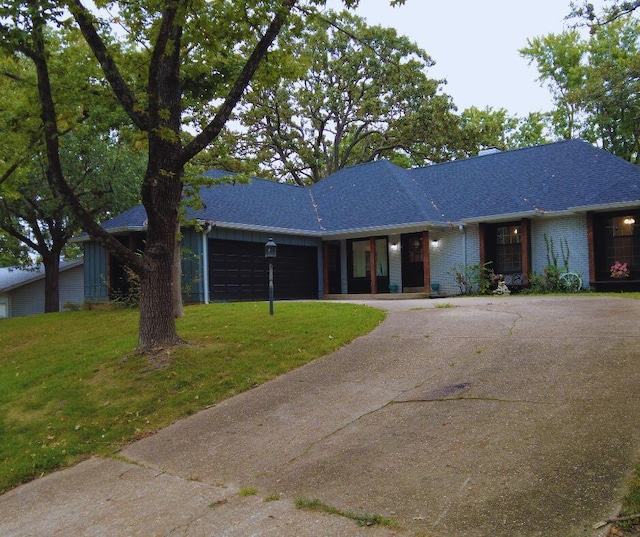 single story home with aphalt driveway, an attached garage, a porch, a front yard, and brick siding